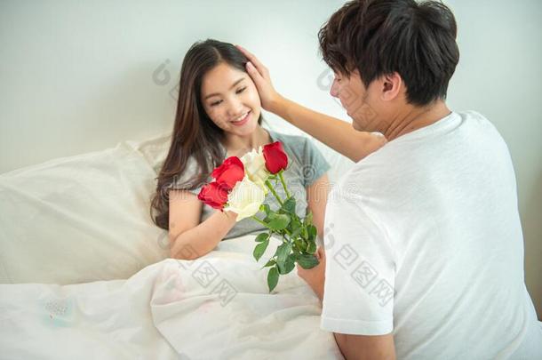 亚洲人年幼的男人使惊奇女孩和玫瑰向床,丈夫鼓励