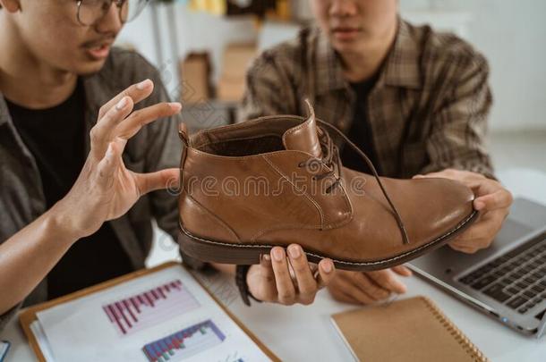 年幼的亚洲人人商人闲谈关于产品关于鞋子