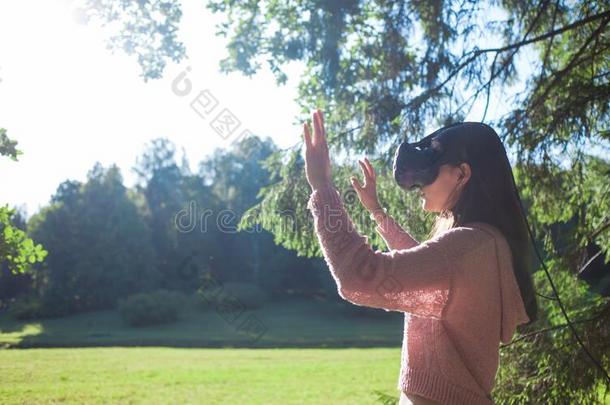 实质上的森林.一年幼的女人采用VirtualReality虚拟现实眼镜看台在下面指已提到的人特尔