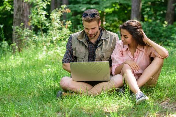 对年轻用钱空闲时间在户外和便携式电脑.男人和女孩int.看