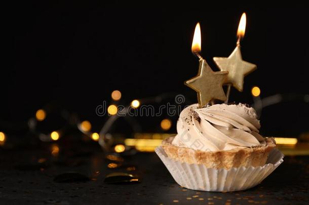 生日纸杯蛋糕和蜡烛向表反对黑的背景,
