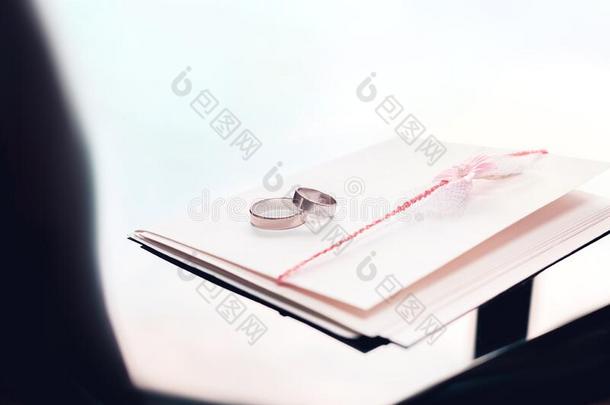 信封装饰和粉红色的花和两个婚礼戒指