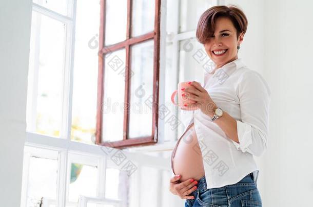 怀孕的女人等候为未出生的婴儿微笑室内的