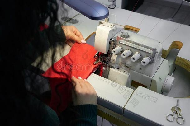 年幼的女人使用专业的锁边缝纫机器采用工作