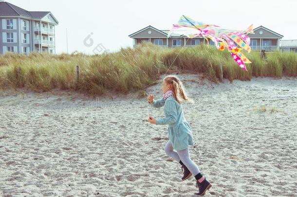 欢乐的小的女孩跑步采用衣服向海滩和风筝