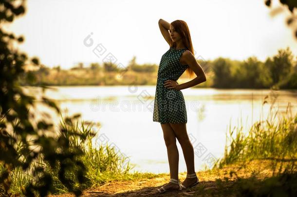 年幼的女人起立和享有夏一天和湖在后面