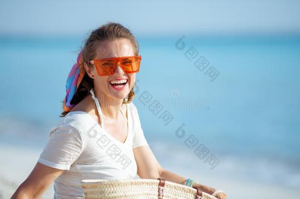 幸福的健康的女人向海岸采用桔子太阳镜