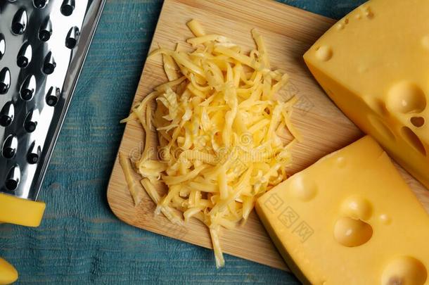 美味的搓碎的奶酪向蓝色木制的表,平的放置