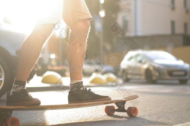 光-具有皮的滑冰者享有冲浪板乘向和煦的：照到阳光的城市大街
