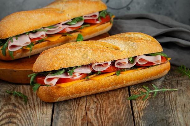 两个长的法国长面包三明治和芝麻菜,部分关于新鲜的tomato番茄