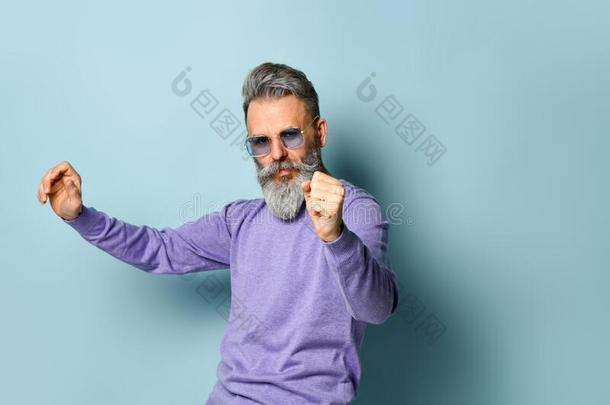 灰色-有毛发的老年的男人采用紫色的毛衣,太阳镜.Danc采用g和
