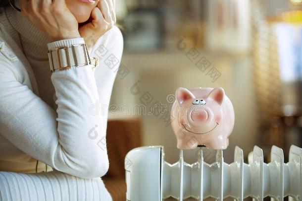 特写镜头向不幸的时髦的女人在近处暖气片和小猪银行