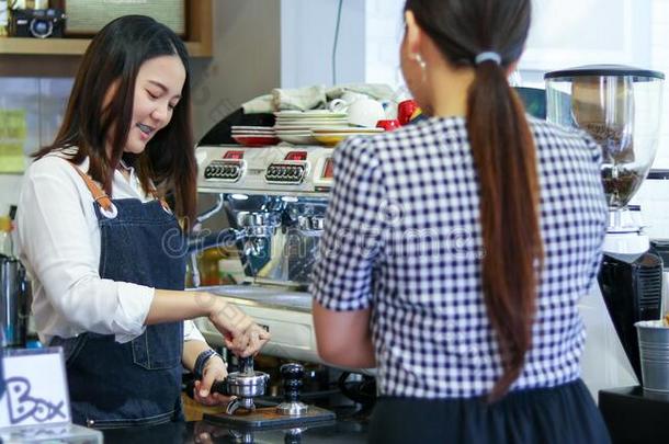 咖啡馆准备咖啡的员工服务顾客和女人是（be的三单形式支付的为咖啡豆在旁边克雷迪
