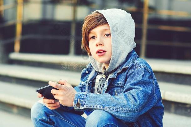 青春期前的男孩使用智能手机在学校在外面.聪明的男孩佩林