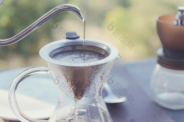 关-在上面手滴下咖啡豆制造涌出越过咖啡豆和热的水