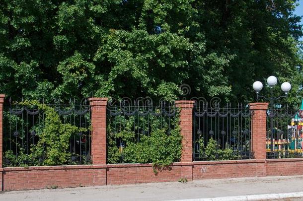 美丽的栅栏栅栏使关于红色的砖采用指已提到的人绿色的植物的叶子