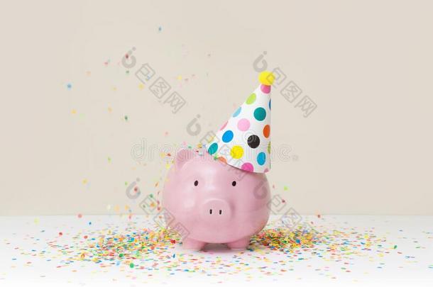 粉红色的小猪银行和生日盖和颜色五彩纸屑向米黄色波黑