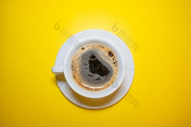 白色的咖啡豆杯子和起泡沫茶杯托向一明亮的黄色的b一ckground