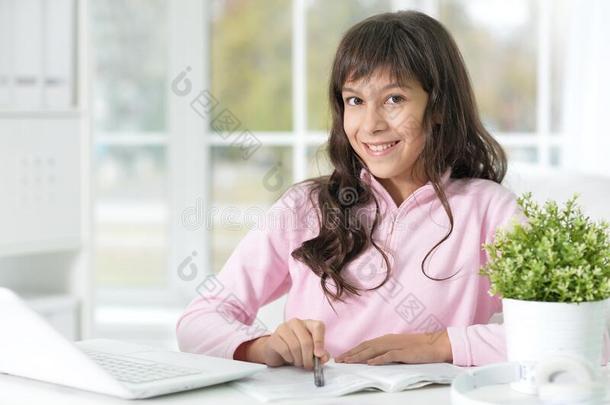 美丽的女孩和便携式电脑学习在书桌