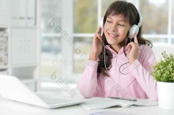 小的女孩使用便携式电脑在期间学习在书桌