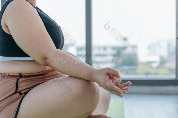 肥的和加大小女人做瑜伽和默想在室内在健身房