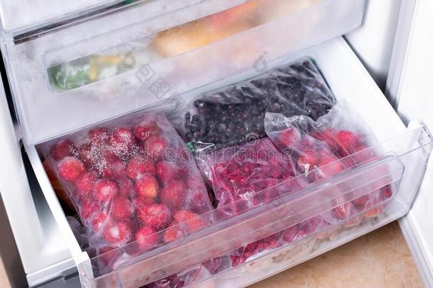 塑料制品袋和不同的冷冻的浆果采用冰箱