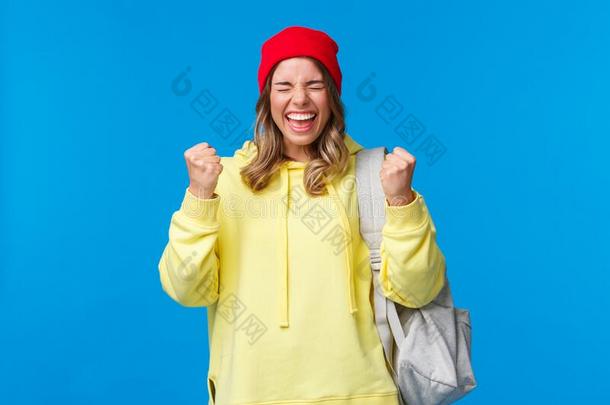 幸福的欢乐的亚麻色的女孩采用红色的无檐小便帽和黄色的连帽衫,关