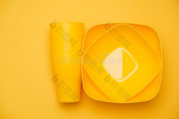 黄色的塑料制品杯子和盘子向黄色的背景.烹饪术小卡车
