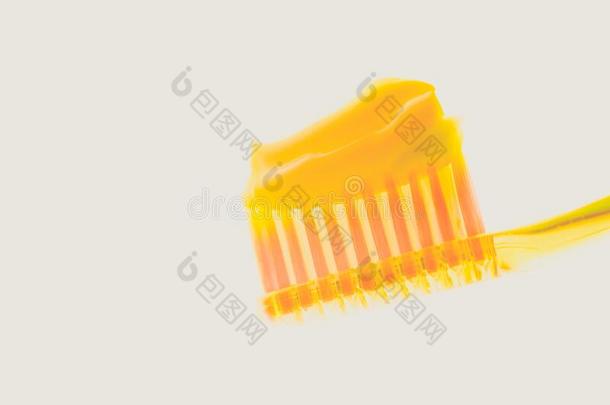 黄色的塑料制品牙刷和甜瓜牙膏向一隔离的英语字母表的第2个字母
