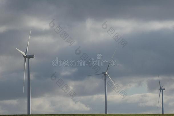 行关于num.三风涡轮机采用一绿色的田和一多云的天采用