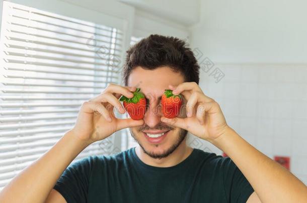 一年幼的男人关他的眼睛和成熟的草莓