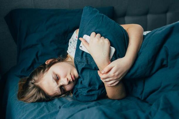 悲哀的情绪低落的年幼的女人热烈地拥抱枕头说谎采用床单独的,在上面