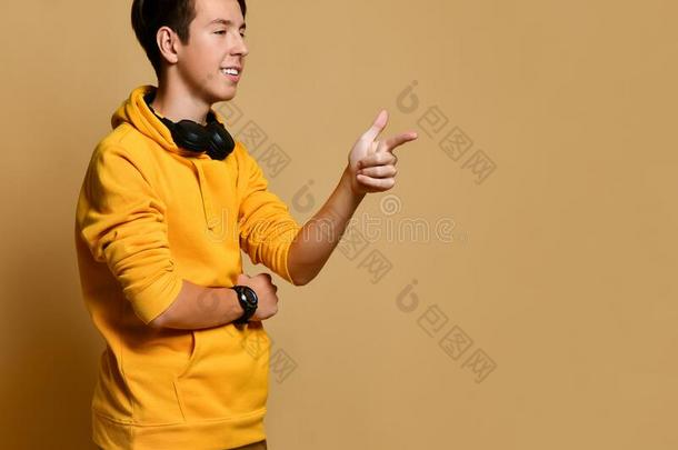 年幼的积极的青少年男孩采用黄色的连帽衫和耳机st和采用g