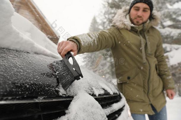 年幼的男人清洁雪从汽车向冬一天