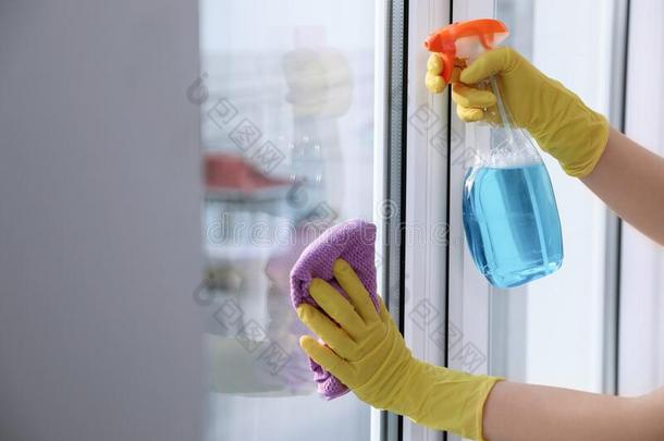 女人清洁窗在家.家庭chore的复数