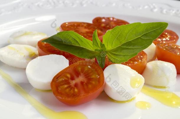 红白小碟沙拉和成熟的番茄和意大利干酪和新鲜的罗勒属植物