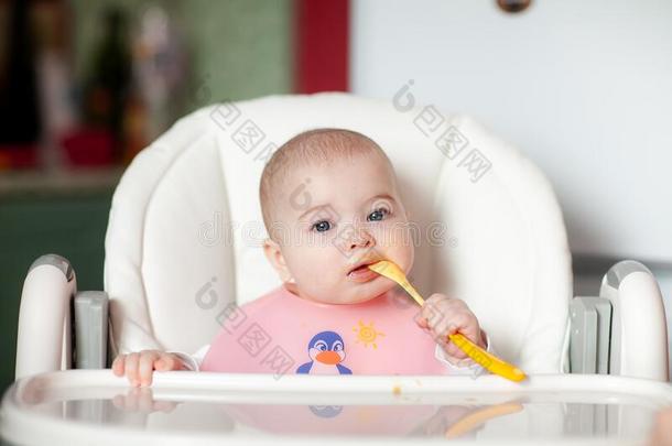 给食6月亚洲人婴儿女孩向高的椅子.妈妈喂养混合
