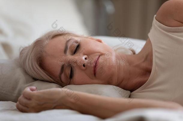 沉静的年长的女人睡眠向舒适的枕头采用卧室.