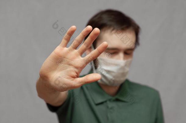 男人采用保护的医学的面具和show采用g手势停止病毒