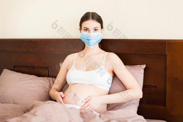 怀孕的女人采用保护的医学的面具有日冕形病毒和是（be的三单形式