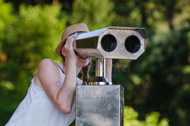 年幼的女孩有样子的通过旅行者望远镜向公园背景