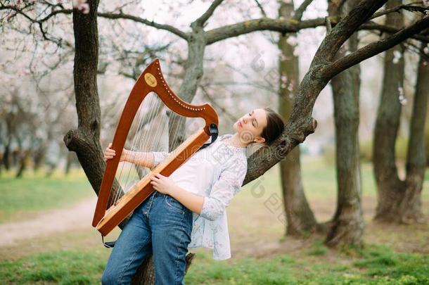 女人弹竖琴者有享有在开花花园和演奏竖琴