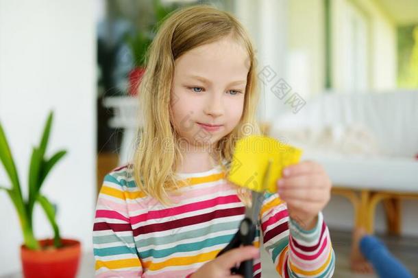 年幼的女孩锋利的富有色彩的纸和剪刀在家.Cre在iv