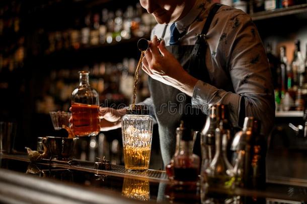 酒吧间销售酒精饮料的人使用高脚杯小心谨慎地涌出喝进入中玻璃摇动者