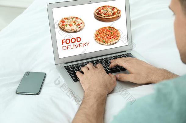 男人使用便携式电脑为在线的食物命令在的时候检疫期.快乐