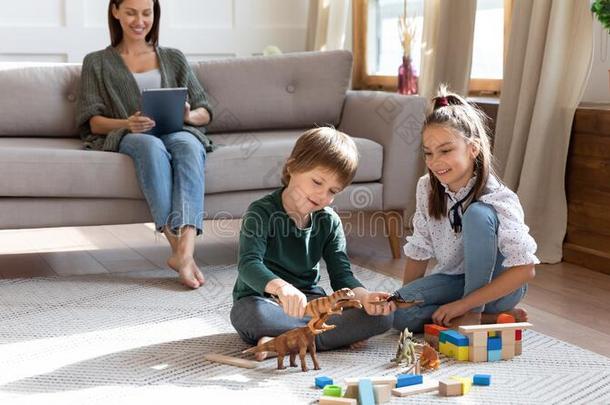 微笑的小孩演奏玩具向地面,在期间妈妈保姆使用computable可计算的