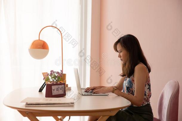 <strong>舒适</strong>的年幼的亚洲人女人<strong>自由</strong>作家坐向粉红和白色的design设计