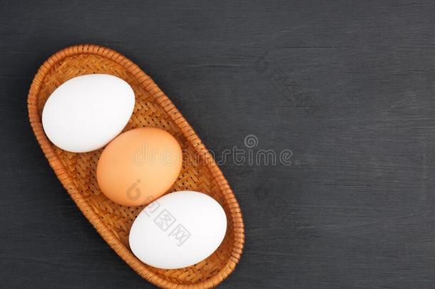 生的鸡卵采用一柳条杯子向bl一ck木制的b一ckground和