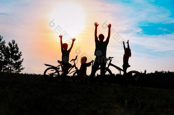 幸福的家庭向自行车和小型摩托车在日落n在ure,爸爸和小孩