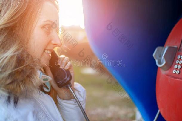 女人讲话在旁边公用电话在春季和煦的：照到阳光的一天